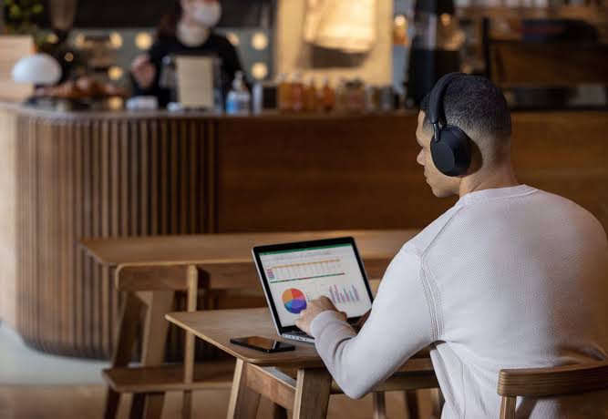 Pessoa de fones de ouvido concentrada no notebook em uma cafeteria