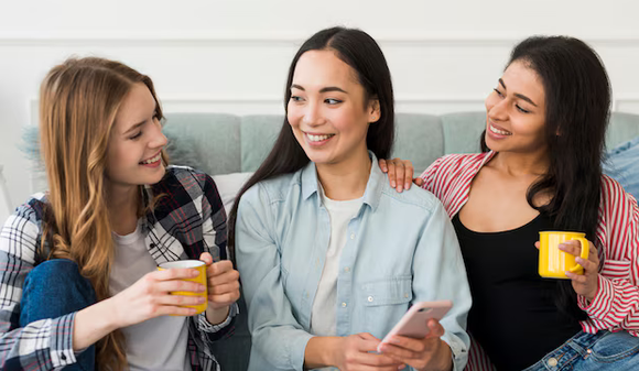 Três amigas conversando e rindo juntas no sofá