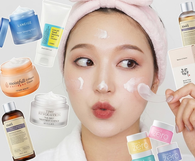 Mulher com faixa de cabelo rosa cercada de produtos de skincare coreano, com creme aplicado no rosto